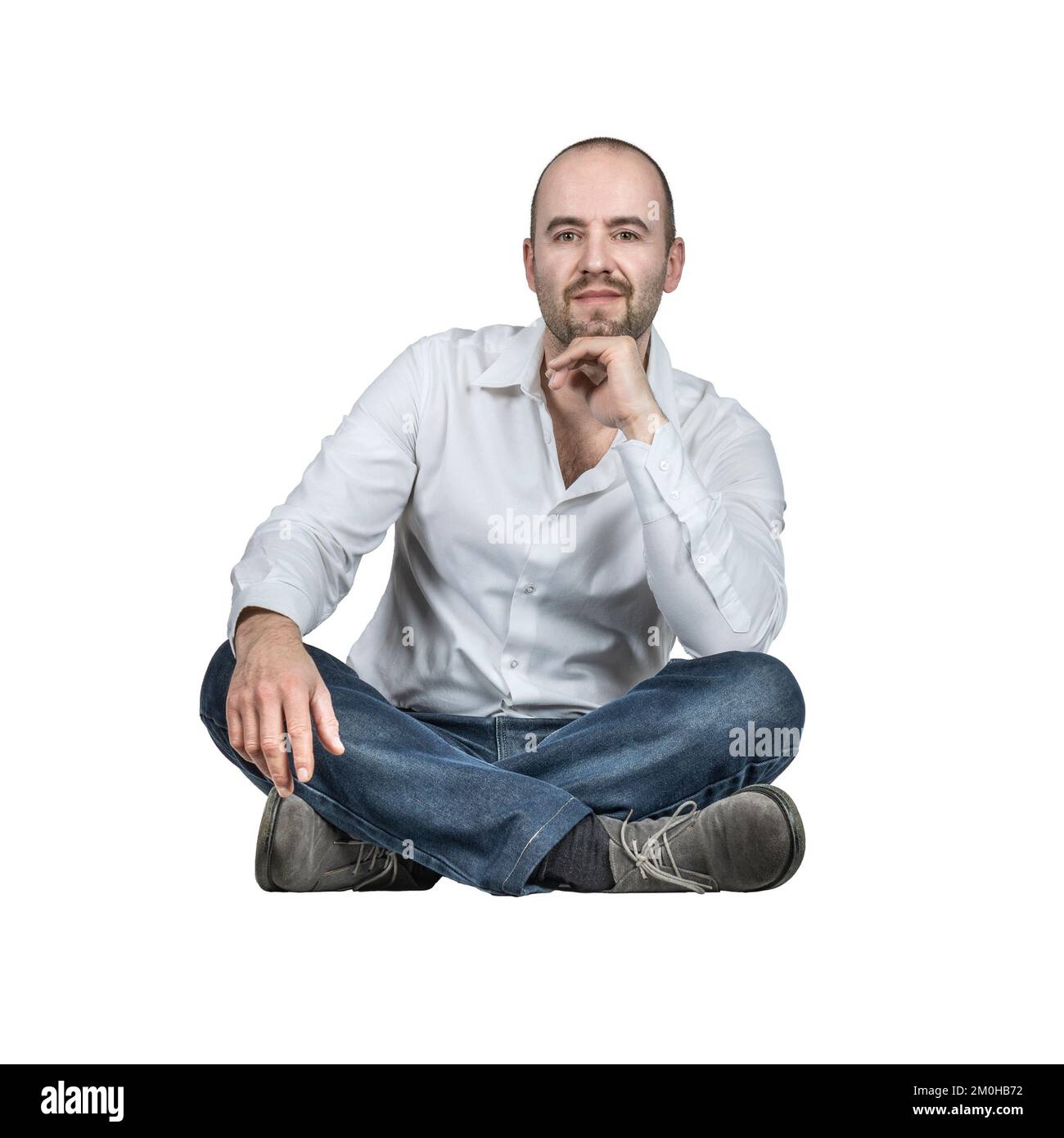 Mann sitzt mit gekreuzten Beinen isoliert auf weiß Stockfoto