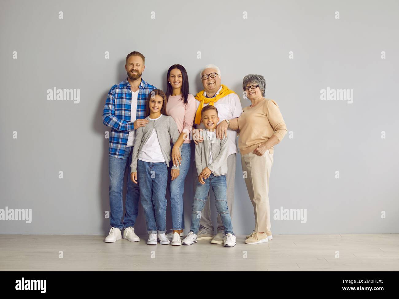 Porträt einer glücklichen, fröhlichen Familie, die alle zusammen an der Wand im Studio steht Stockfoto