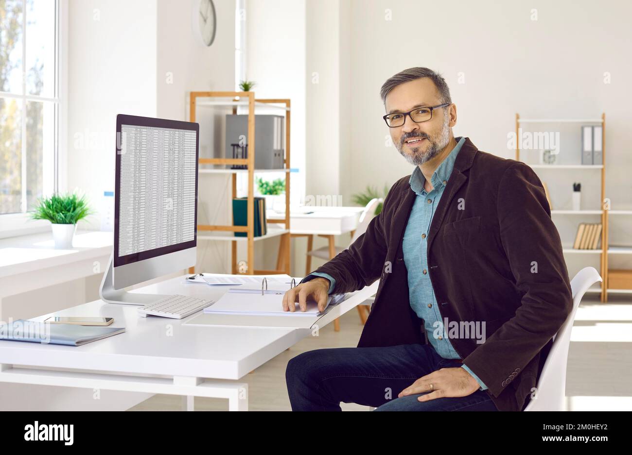 Geschäftsmann oder Finanzbuchhalter, der mit einem Desktop-Computer an seinem Büroschreibtisch sitzt Stockfoto