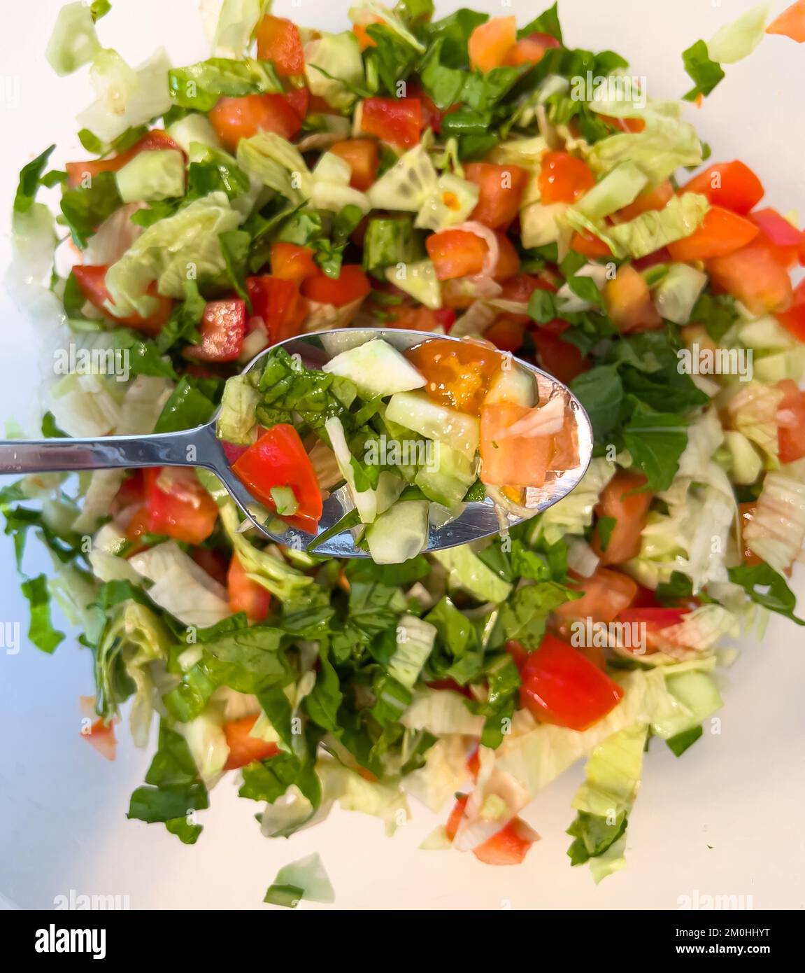 Blick von oben auf den Salat im Löffel. Türkischer Schäfersalat. Nahaufnahme gewürfelter Salat. Stockfoto