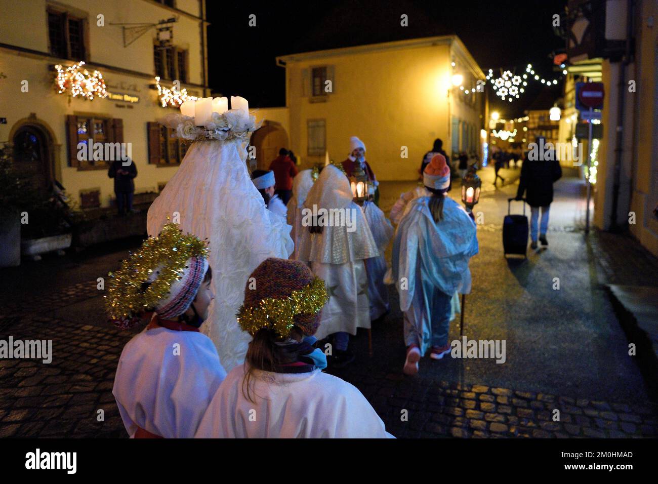 Frankreich, Haut Rhin, Eguisheim, der Christkindel mit seiner Krone aus Kerzen und die Engel begleiten die vielen Kinder, die ihre Laternen für die Lichterprozession in den Gassen der Stadt halten, sie ehrt die Heilige Lucia, eine der traditionellen Charaktere der elsässischen Weihnachten Stockfoto