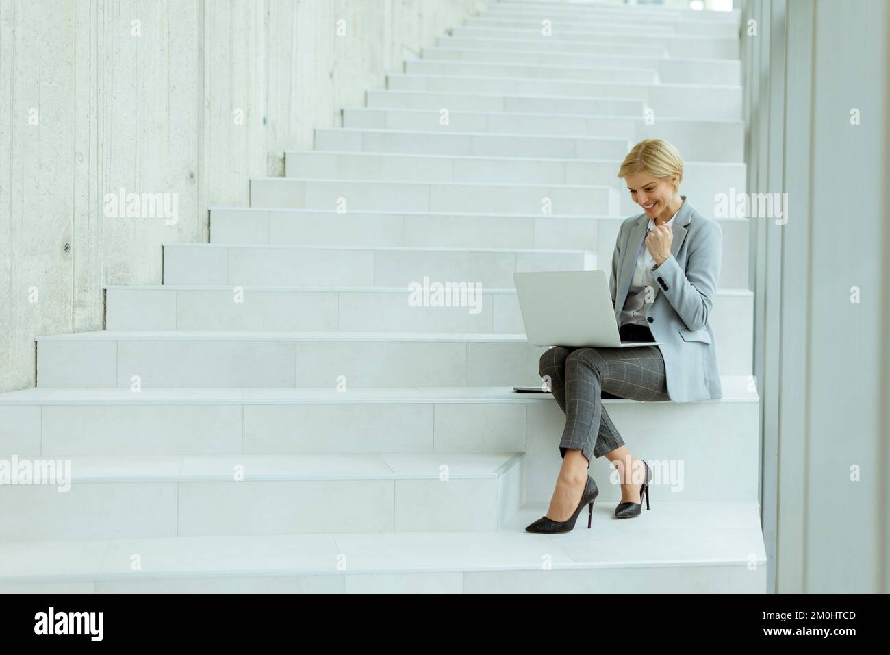 Geschäftsfrau, die auf der modernen Bürotreppe an einem Laptop arbeitet Stockfoto