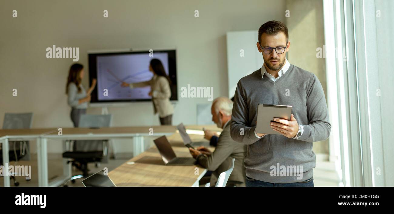 Schöner junger moderner Geschäftsmann mit digitalen Tablet im Büro Stockfoto