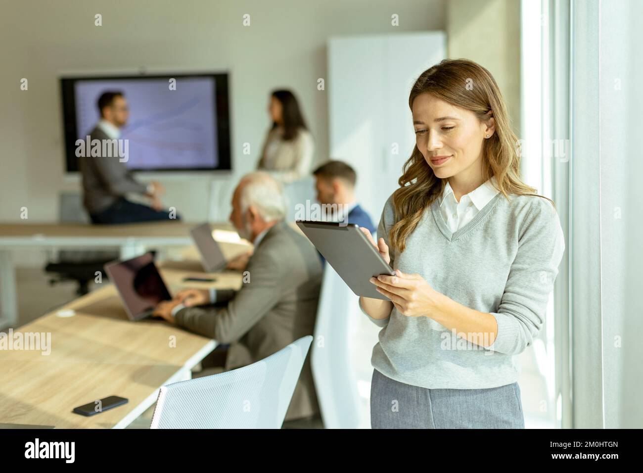 Hübsche junge geschäftsfrau beim Start Büro mit digitalen Tablet vor Ihrer Kollegen als Team Leader Stockfoto