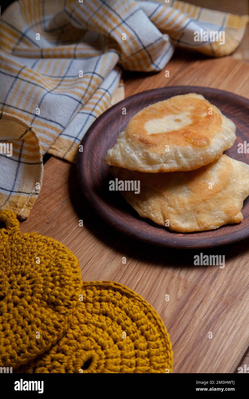 Tonplatte mit zwei einzelnen gebratenen Pasteten mit Fleisch auf Holztisch. Tatarische traditionelle Pasteten. Stockfoto