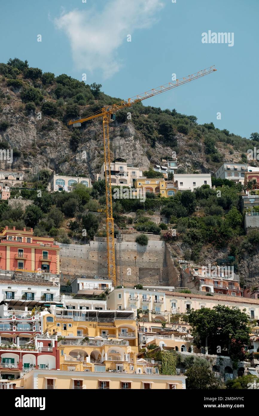 Die farbenfrohen Häuser, Geschäfte und Hotels von Positano schichten vertikal auf den Klippen mit Blick auf den Yachthafen grande Beach Italien. Das Bild zeigt den Kran in Schießerei. Stockfoto