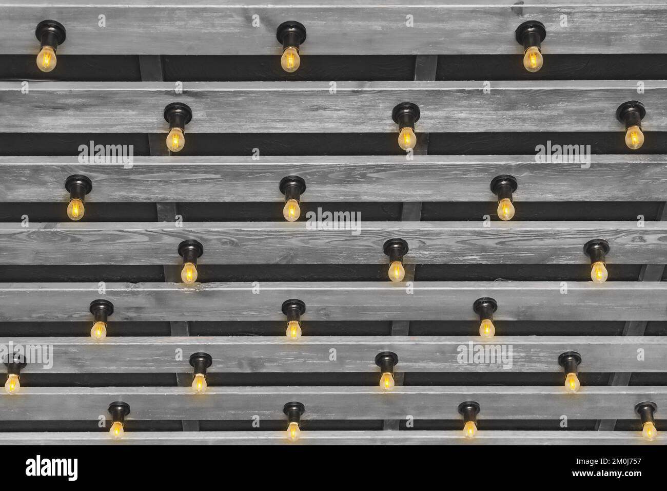 Modernes Innendesign aus Holz mit grauer Plankendecke und Hintergrund mit Glühlampen. Stockfoto
