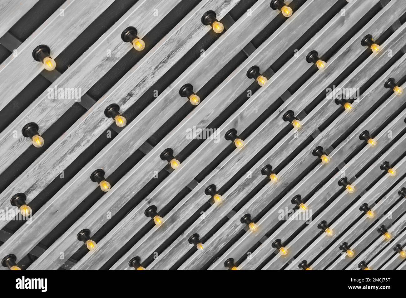 Modernes Innendesign aus Holz mit grauer Plankendecke und Hintergrund mit Glühlampen. Stockfoto