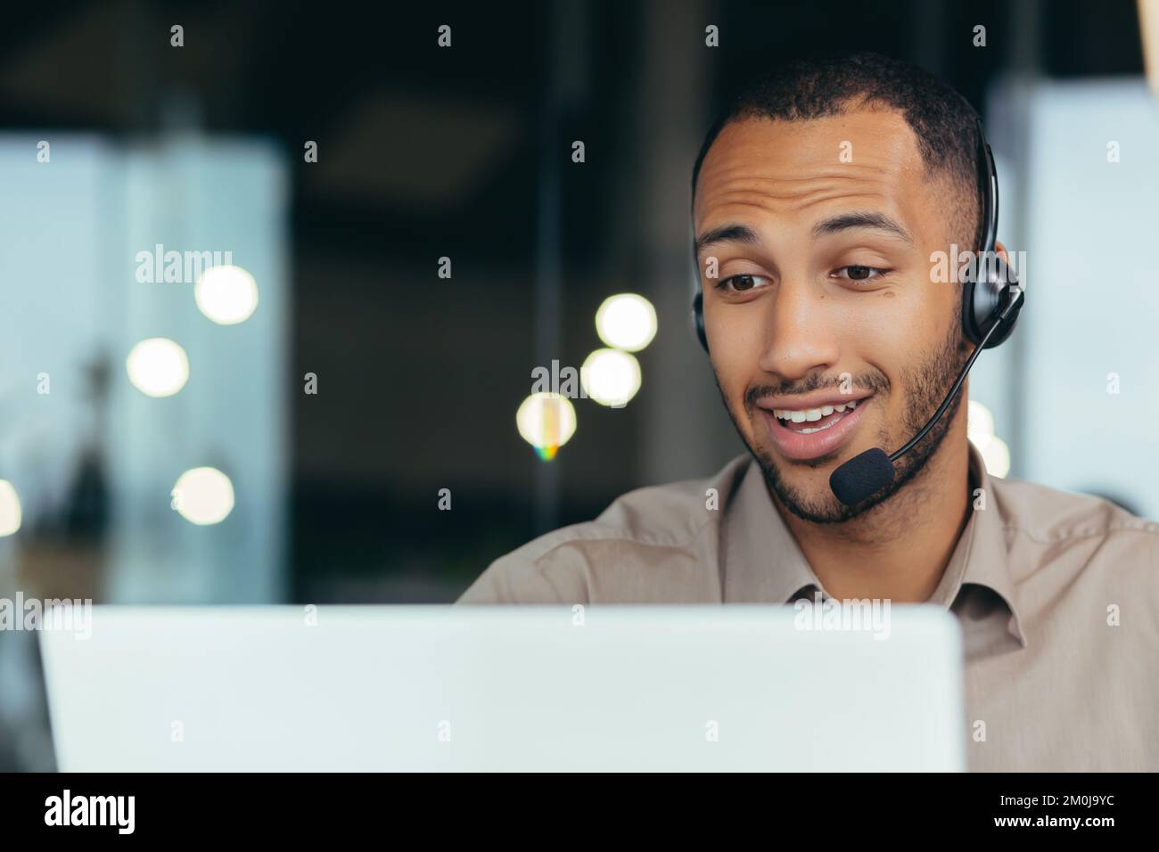 Nahaufnahme. Online lernen. Ein junger gutaussehender afroamerikanischer Student lernt aus der Ferne von einem Laptop, sitzt am Schreibtisch in einem Headset und spricht bei einem Videoanruf. Stockfoto