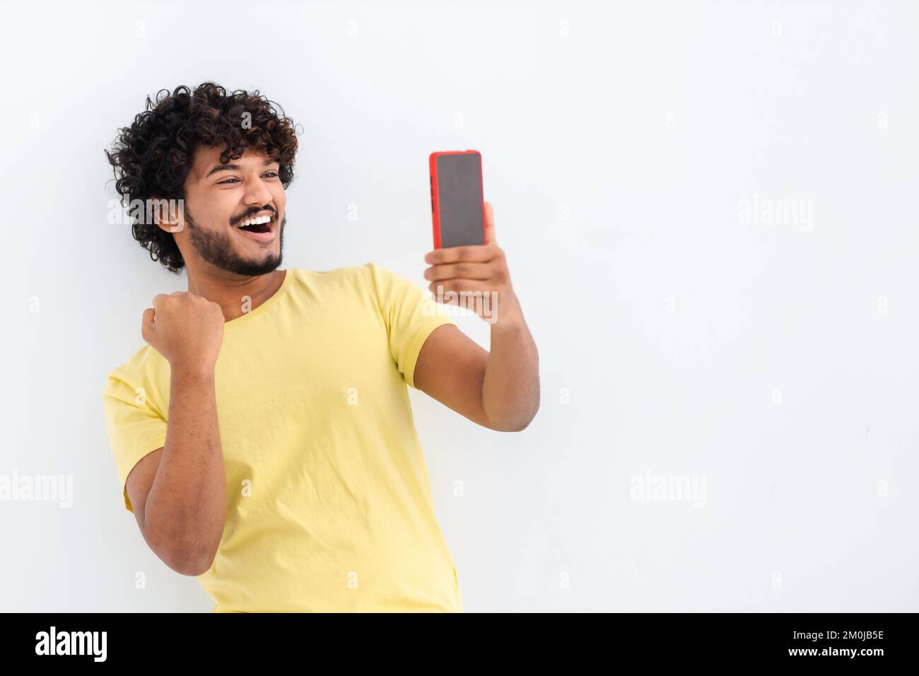 Ein asiatischer Mann, der ein Handy in der Hand hält, gute Nachrichten gelesen hat, Benachrichtigung über den Sieg. Ein Mann, der schreit: "Ja, er bekommt die Bezahlung. Stockfoto