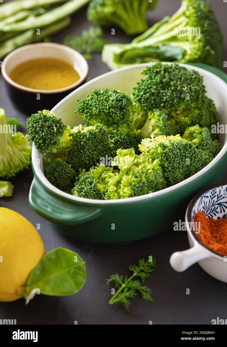 Rohe Zutaten zum Kochen gesunder vegetarischer Lebensmittel Brokkoli grüne Bohnen, Zitrone und Gewürze Stockfoto