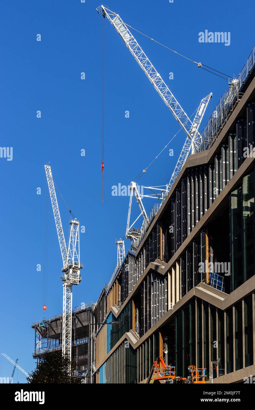 Kräne dominieren den blauen Himmel in diesem markanten Bild des neuen Gebäudes für Google in Progress. Ein riesiges Gebäude im Bau als Büros Stockfoto