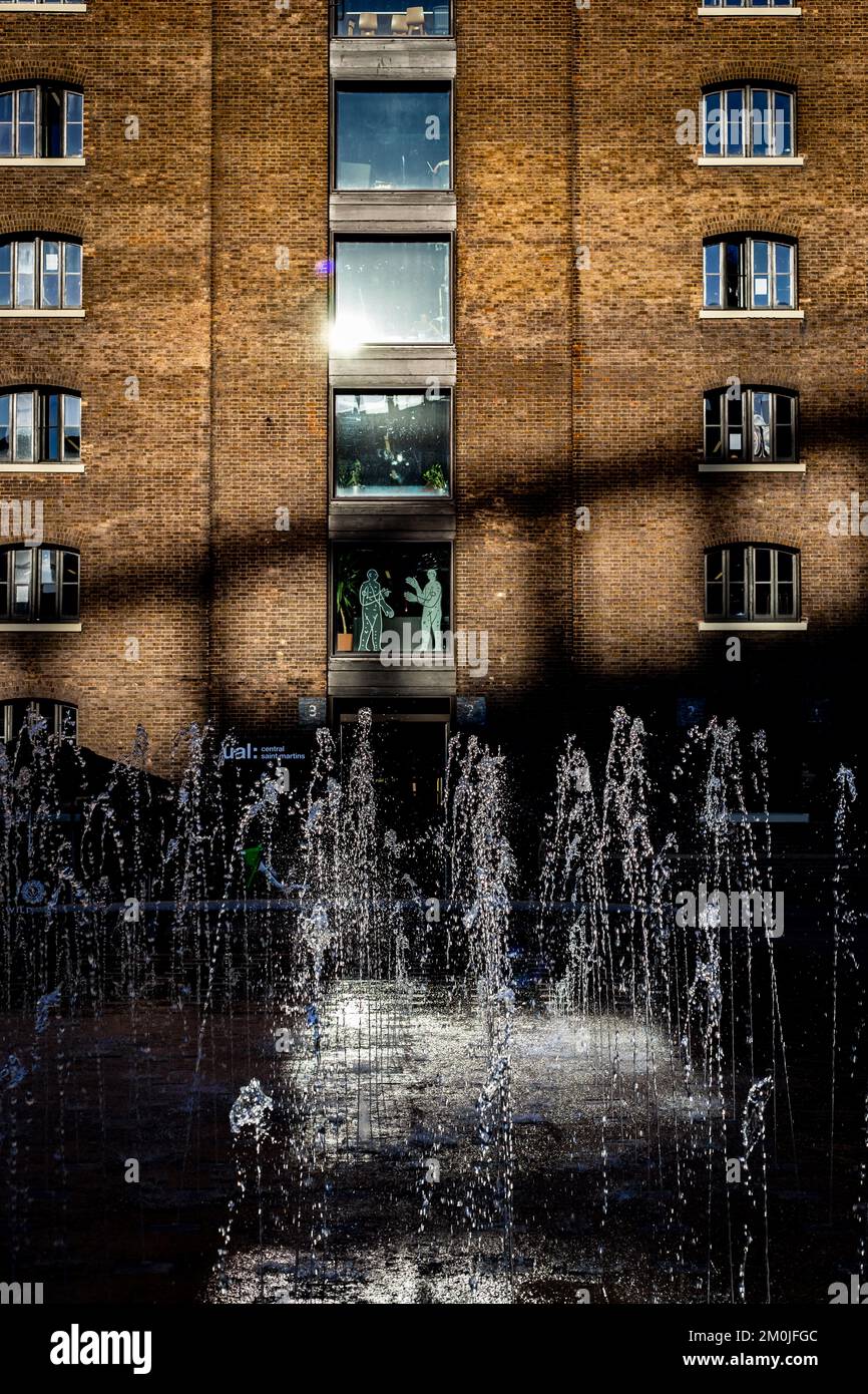 Die St. Martins School of Design ist durch die herrlichen Brunnen zu sehen, die in der scharfen Wintersonne glitzern. Die Schatten auf dem Gebäude sind dramatisch Stockfoto