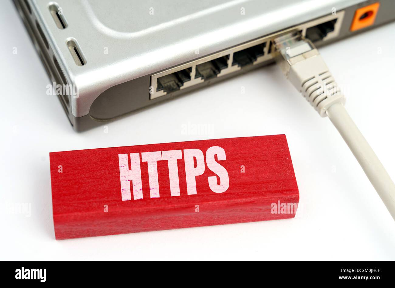 Internet- und Sicherheitskonzept. Auf dem Tisch befindet sich ein Router, der mit dem Netzwerk verbunden ist, neben einer Plakette mit der Aufschrift HTTPS Stockfoto