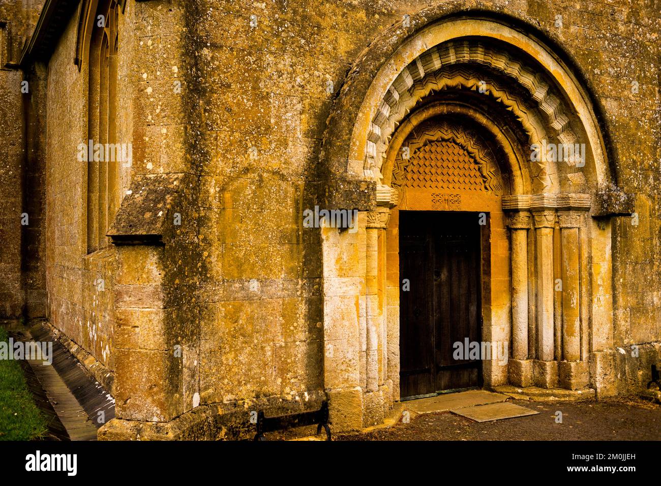 Normannischer oder englischer romanischer Eingang in St. Michaels und All Angels Church in Guiting Power, Cotswold District, England. Stockfoto