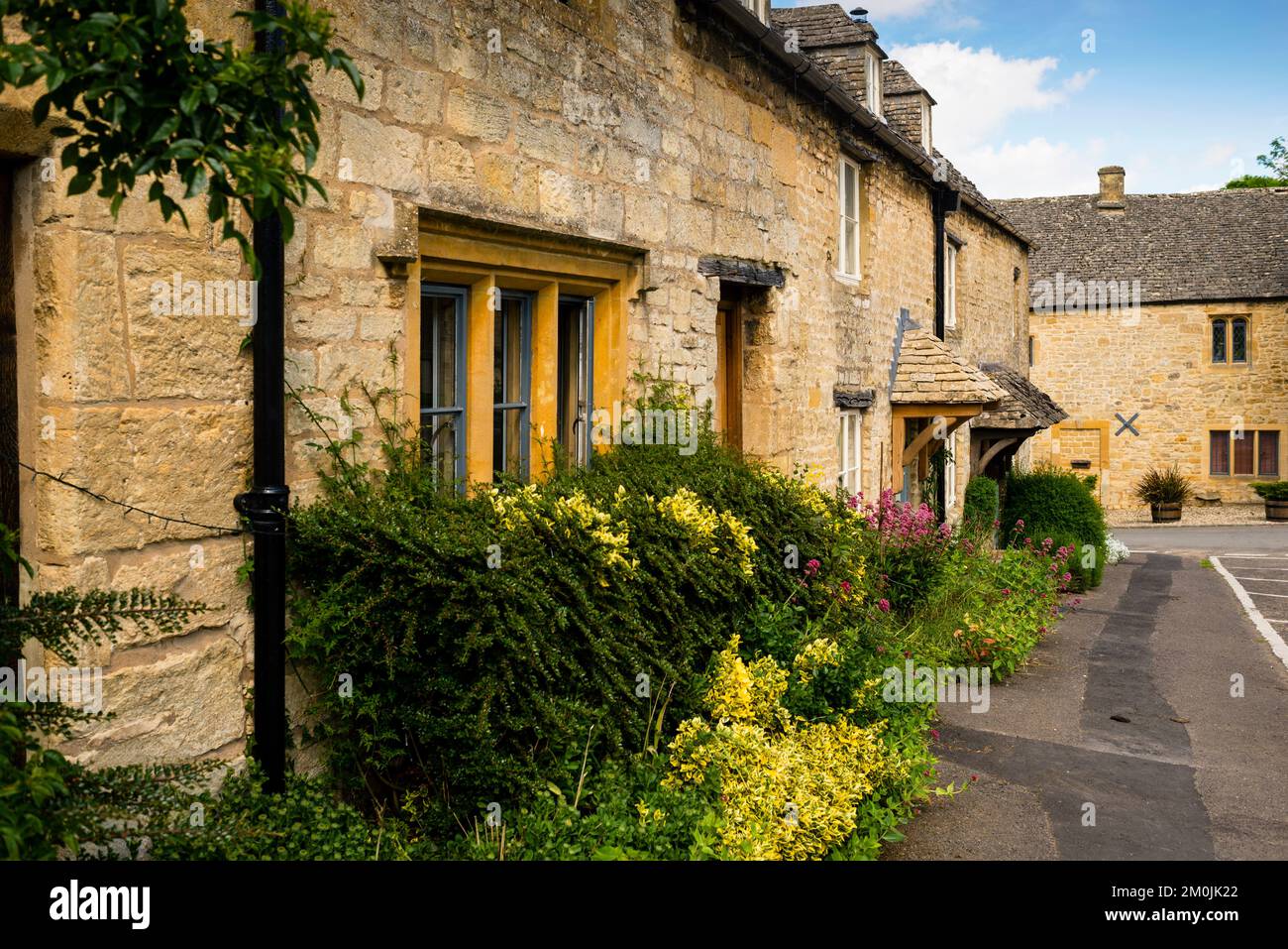 Guiting Power Terrassenhäuser mit Doppelfenstern, Schieferdächern und kleinen Dachdächern in den Cotswolds, England. Stockfoto