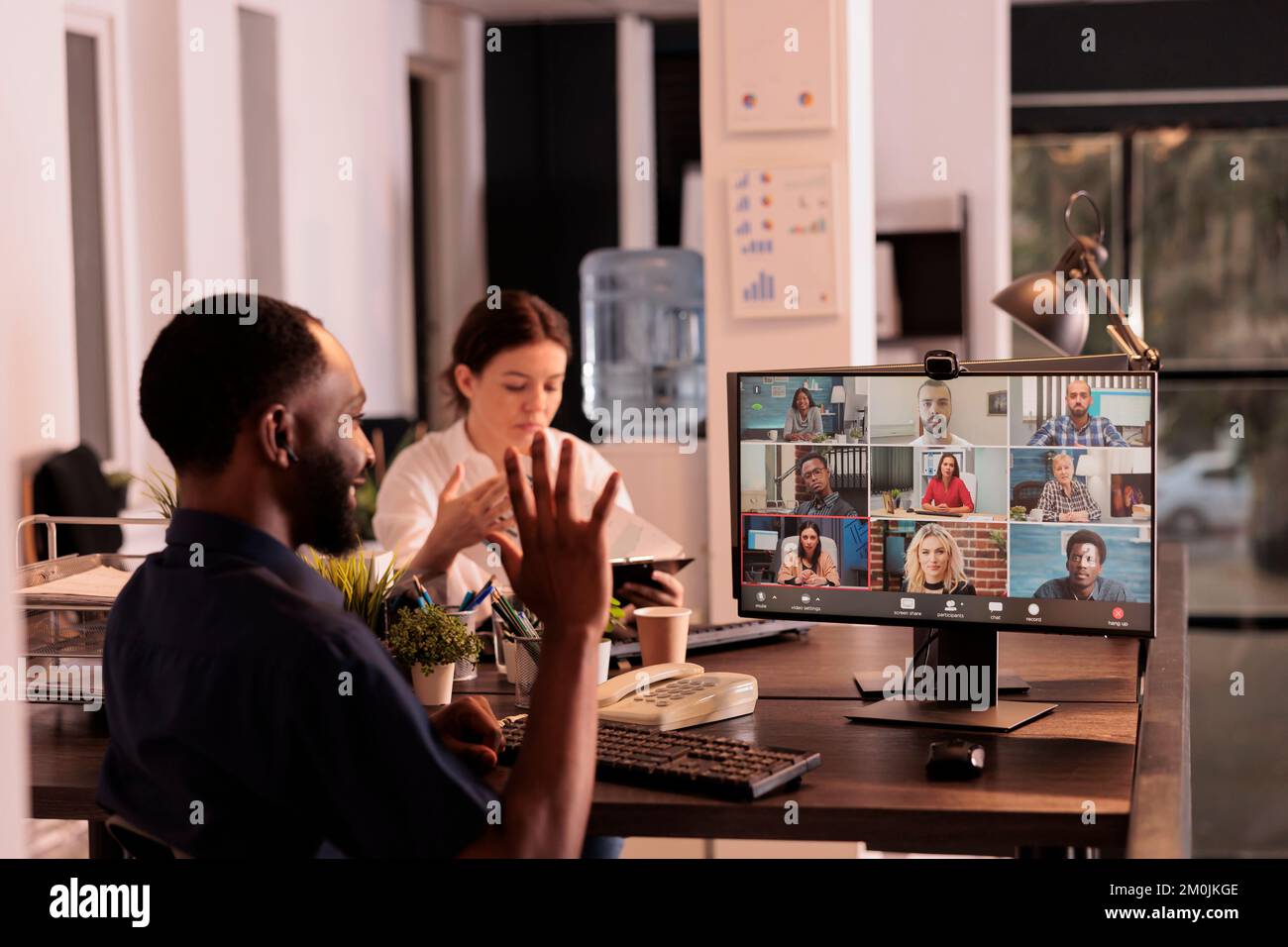 Ein afroamerikanischer Mann, der mit Kollegen im Online-Gruppenchat spricht, Kollegen begrüßt, Hi. winkt Büroangestellter diskutiert Startplan für Webcam-Meetings, Unternehmensvideos, Telearbeit Stockfoto