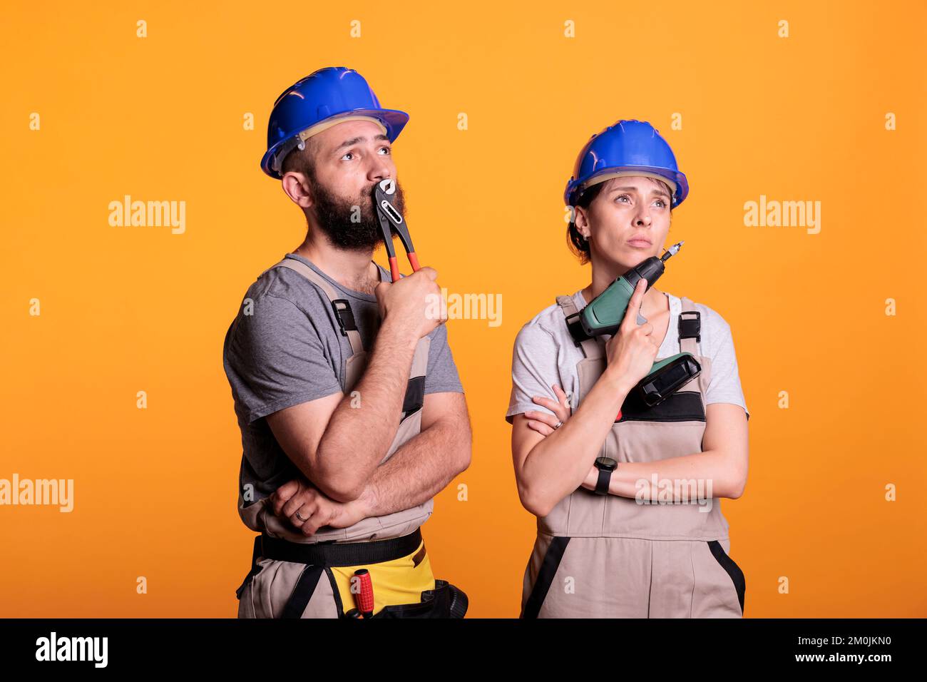 Ein Team von Bauunternehmern, das im Studio Ideen für Bauprojekte sammelt und über die Renovierung einer Lösung nachdenkt, um mit den Umbauarbeiten zu beginnen. Nachdenklicher Mann und Frau mit einer Bohrpistole und einer Zange. Stockfoto