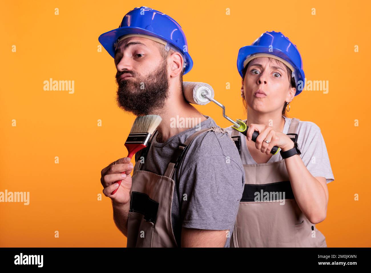 Malerteam, das im Studio Pinsel und Rolle verwendet und mit Werkzeugen an der Malerei arbeitet. Bauarbeiter tragen Overalls und posieren mit Bürsten, erledigen Renovierungsprojekte. Stockfoto