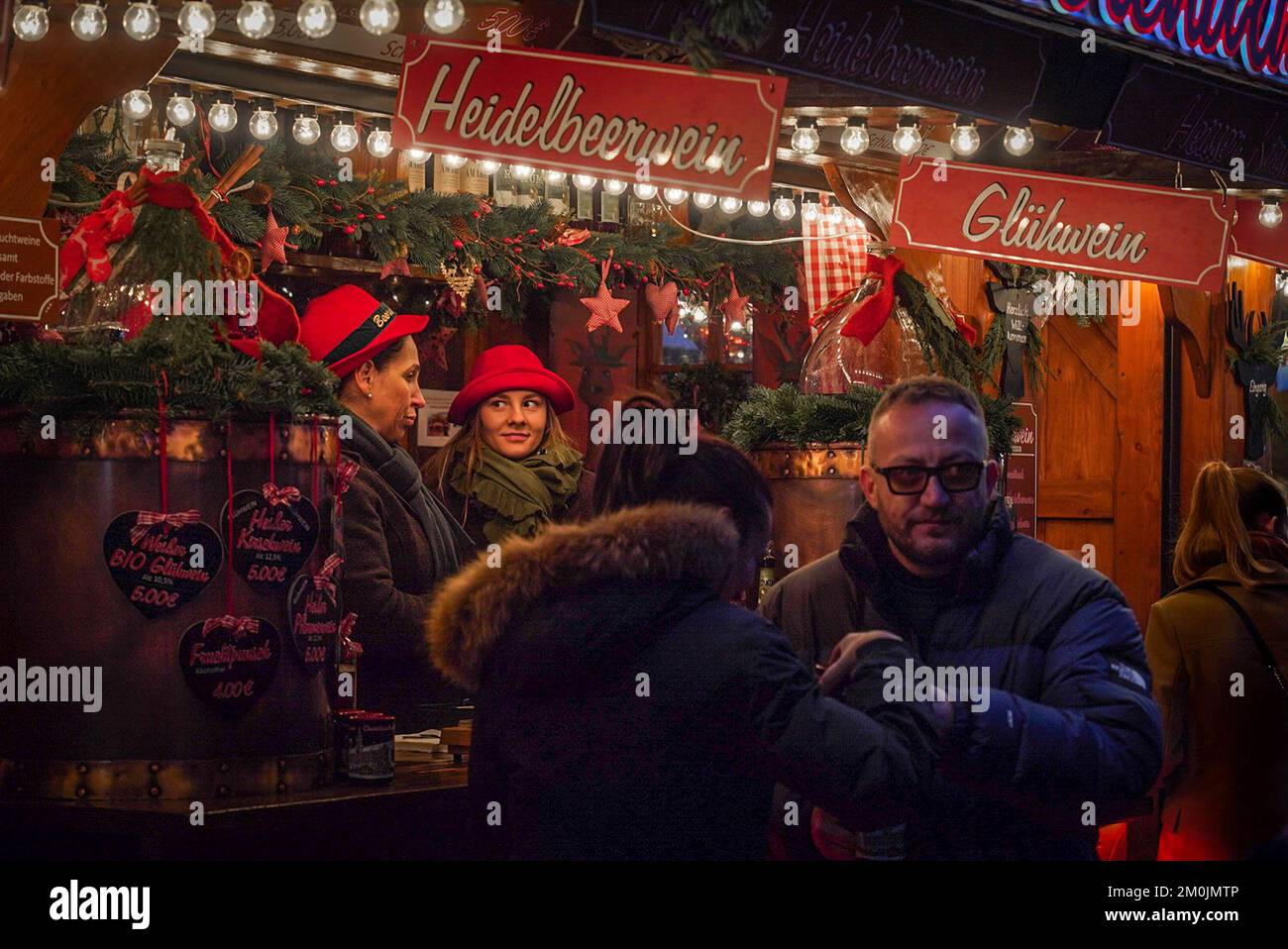 Zwei Verkäuferinnen unterhalten sich nachts in einem Glühwein-Kiosk auf dem Weihnachtsmarkt in München. Stockfoto