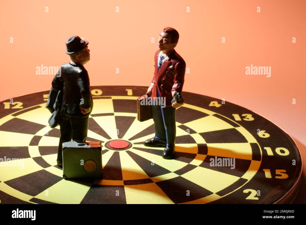 Geschäftsfiguren stehen auf Darttafeln auf warmem Hintergrund Stockfoto