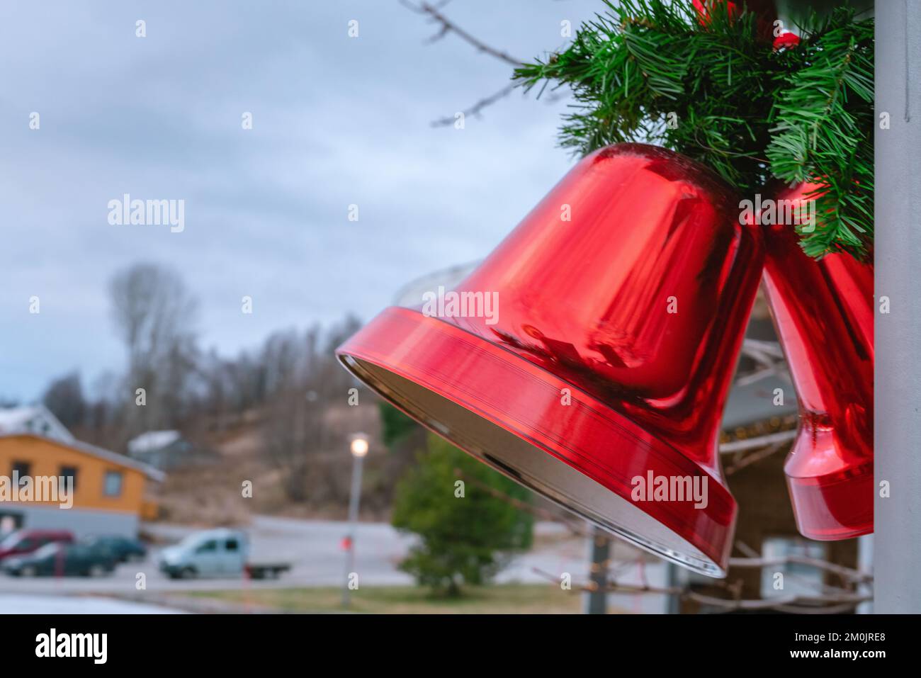 Zwei große weiße rote Glocken mit roter Schleife und Pinienblättern, Straßendekoration, Nahansicht rechts, verschwommener Hintergrund Stockfoto