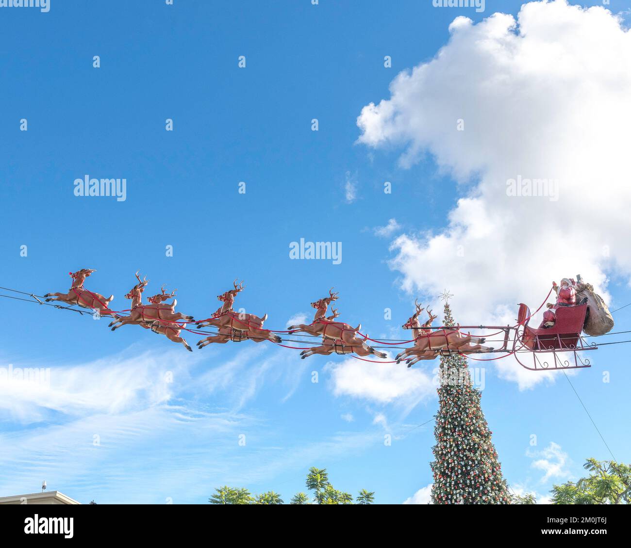 Los Angeles, Kalifornien, USA – 5. Dezember 2022: Der Weihnachtsmann und sein Rentier fliegen in einem Einkaufszentrum in Los Angeles, Kalifornien, durch den blauen Himmel. Stockfoto