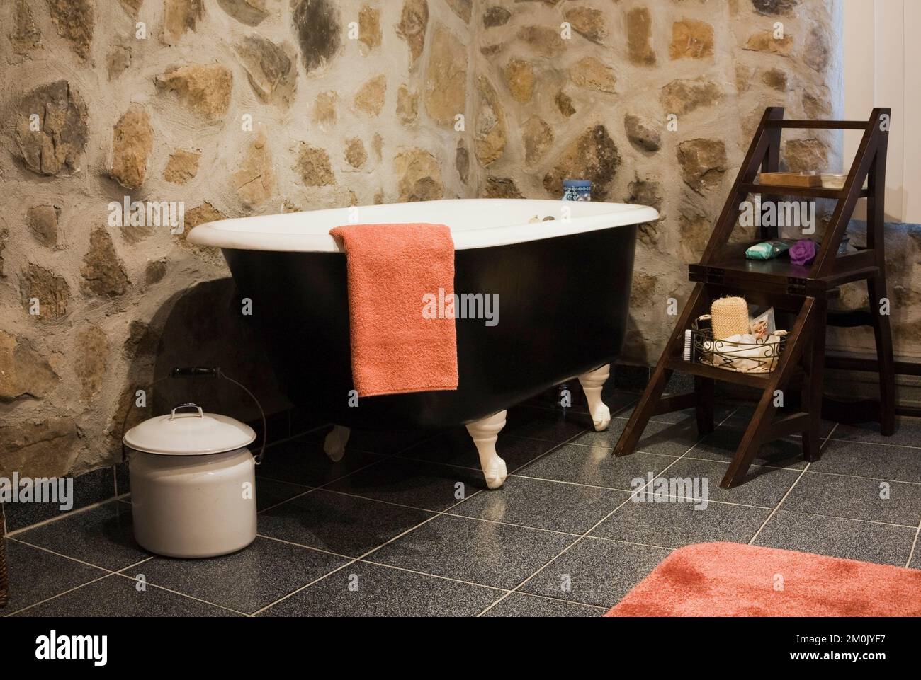 Schwarz-weiße freistehende Badewanne und antike Möbel im Badezimmer im Nachbau des alten Canadiana Cottage-Stil Holz- und Feldsteinhauses. Stockfoto