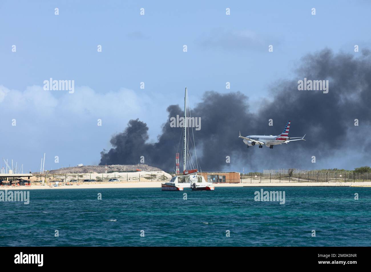 ORANJESTAD, ARUBA - 07. APRIL 2022: Flugzeug landet am Queen Beatrix Airport, während Müll auf der Serlimar Mülldeponie in Oranjestad auf Aruba verbrannt wird Stockfoto