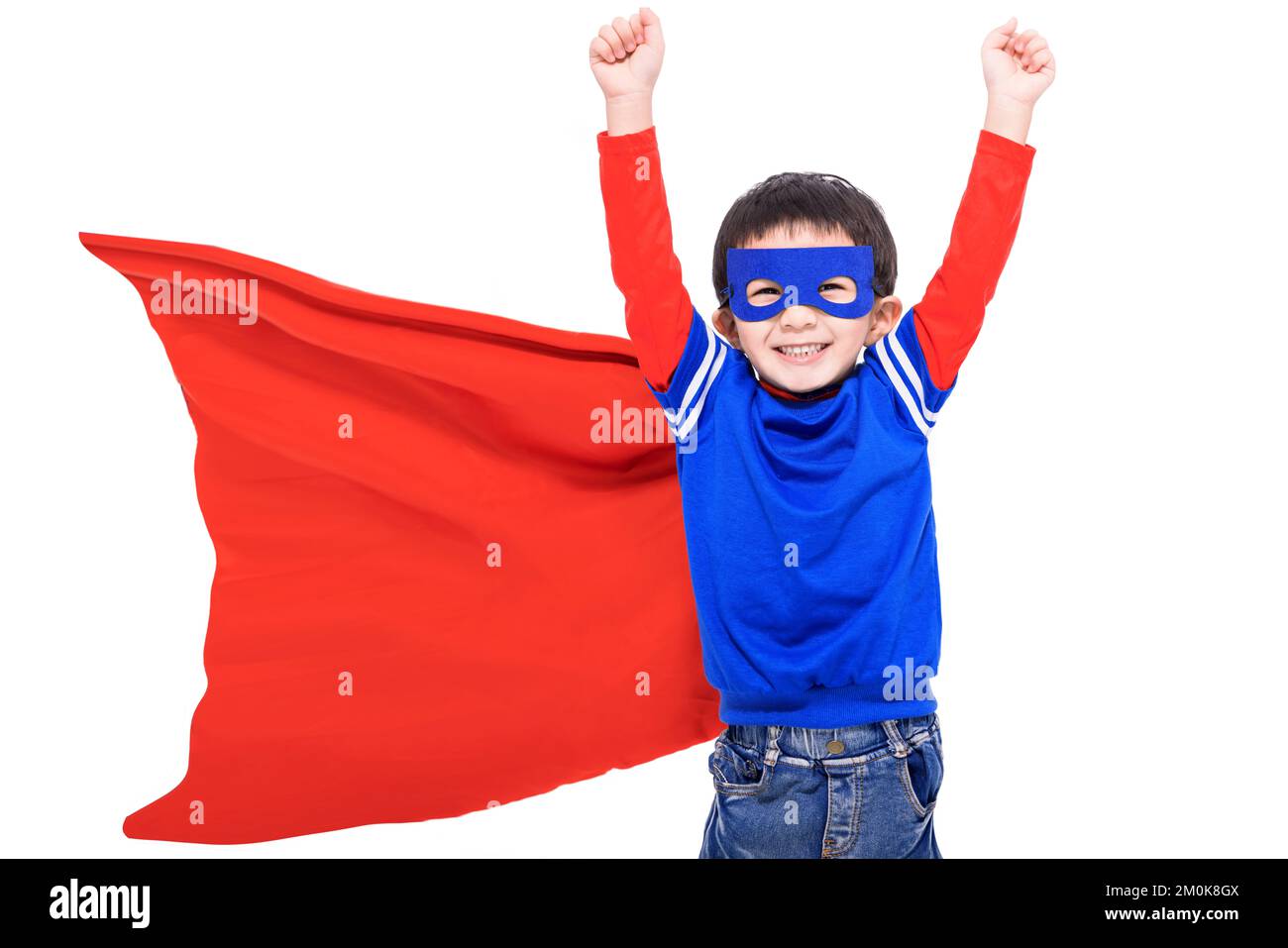 Fröhliches Kind in rotem Superheldenumhang und Maske Stockfoto