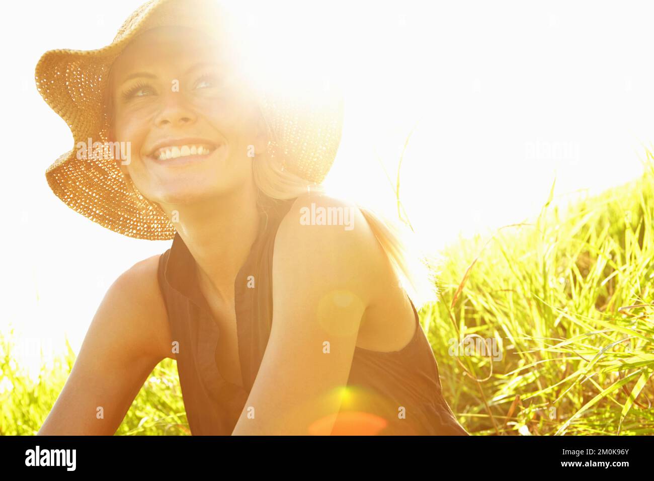 Das Leben zu lieben. Eine wunderschöne, junge blonde Frau, die auf einem Feld sitzt. Stockfoto