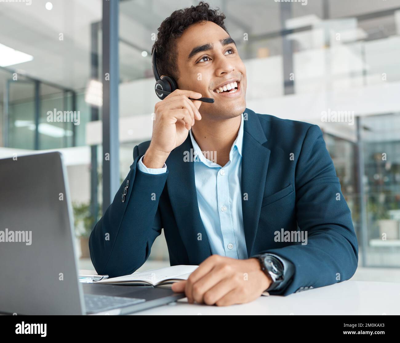 Junge, glückliche Callcenter-Mitarbeiter aus gemischten Rassen beantworten Anrufe, während sie ein Headset tragen und allein bei der Arbeit denken. Ein hispanischer, männlicher Assistent, der lächelt Stockfoto