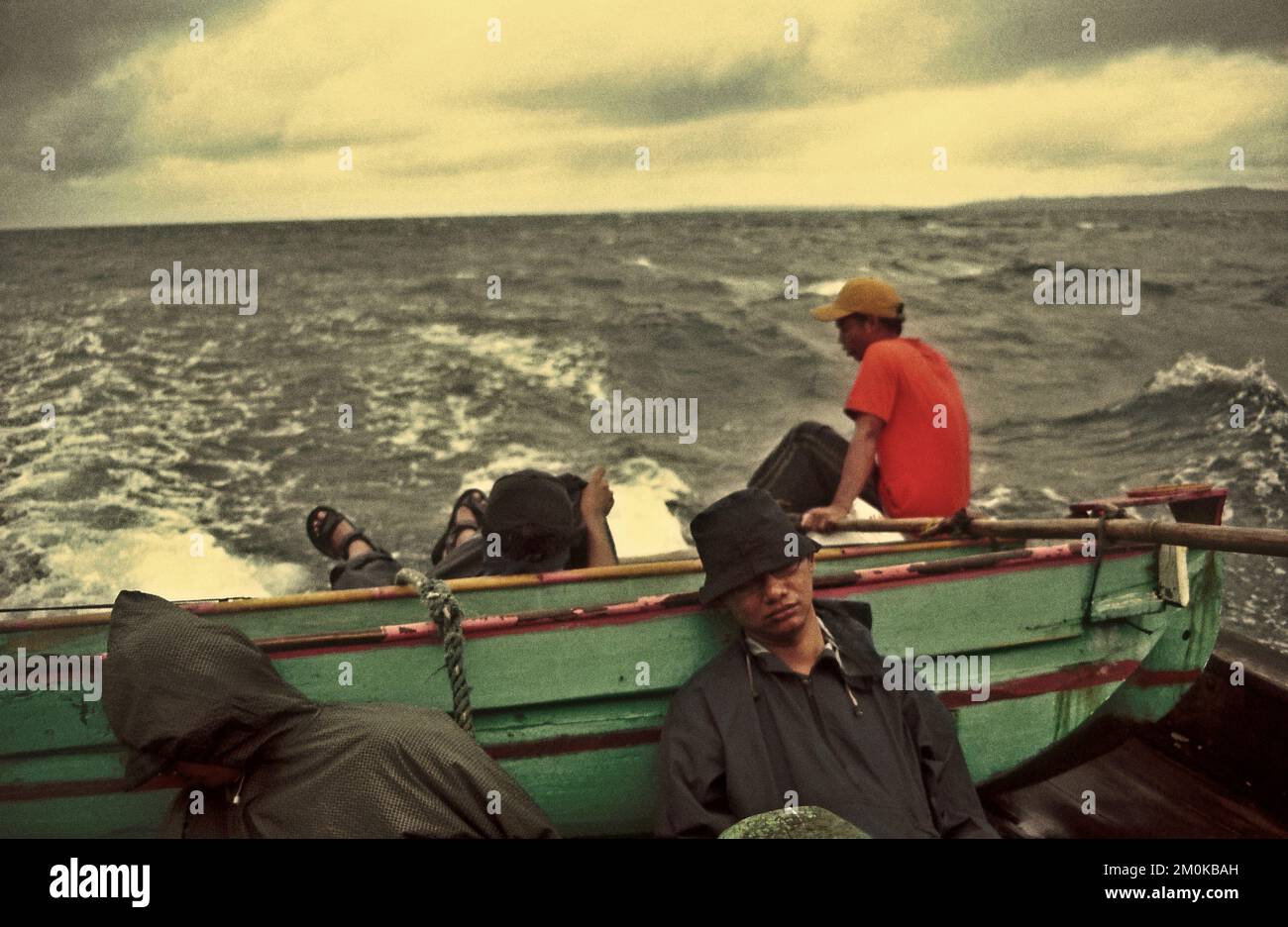 Passagiere und Schiffsbesatzungen schlafen und sitzen auf einem gemieteten Boot, das auf der Sunda-Straße inmitten schlechter Wetterbedingungen segelt und nach dem Verlassen von Peucang Island, einem Teil des Ujung Kulon Nationalparks in Pandeglang, Banten, Indonesien, in die Küstenstadt Sumur fährt. Stockfoto