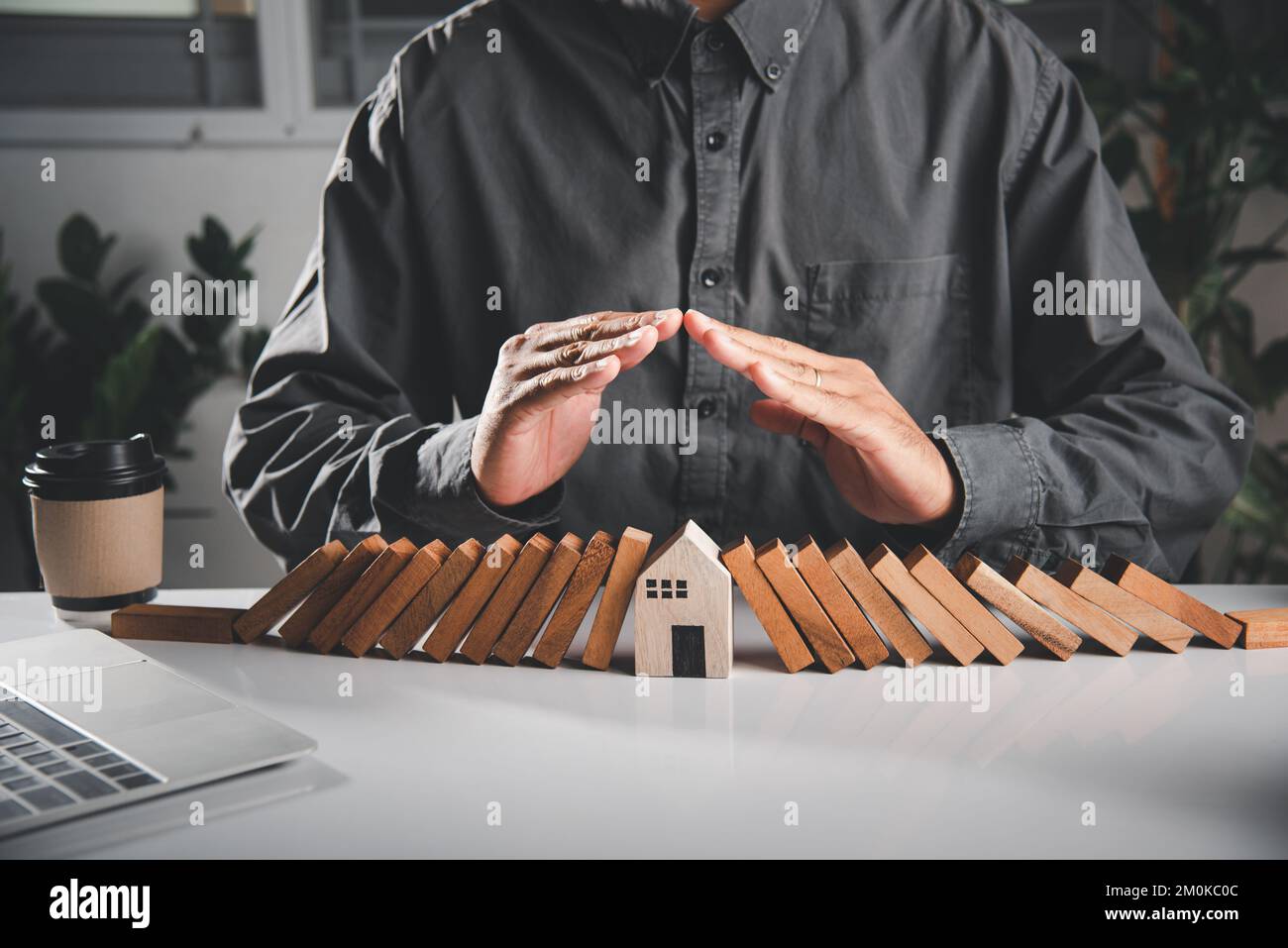 Man Hand blockiert Holzblock aus vielen Reihe fallen Holzblock wie Domino zu Haus Modell Stockfoto