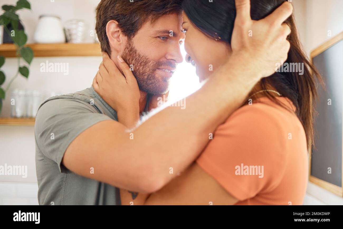 Junge, gemischtrassige Paare, die sich zu Hause in die Augen starren. Ein liebenswerter weißer Freund und eine gemischte Freundin, die im Stehen steht Stockfoto