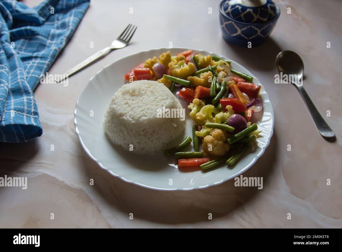 Gesundes Essen gedämpfter Reis und Gemüse sautiert auf einem Teller. Stockfoto