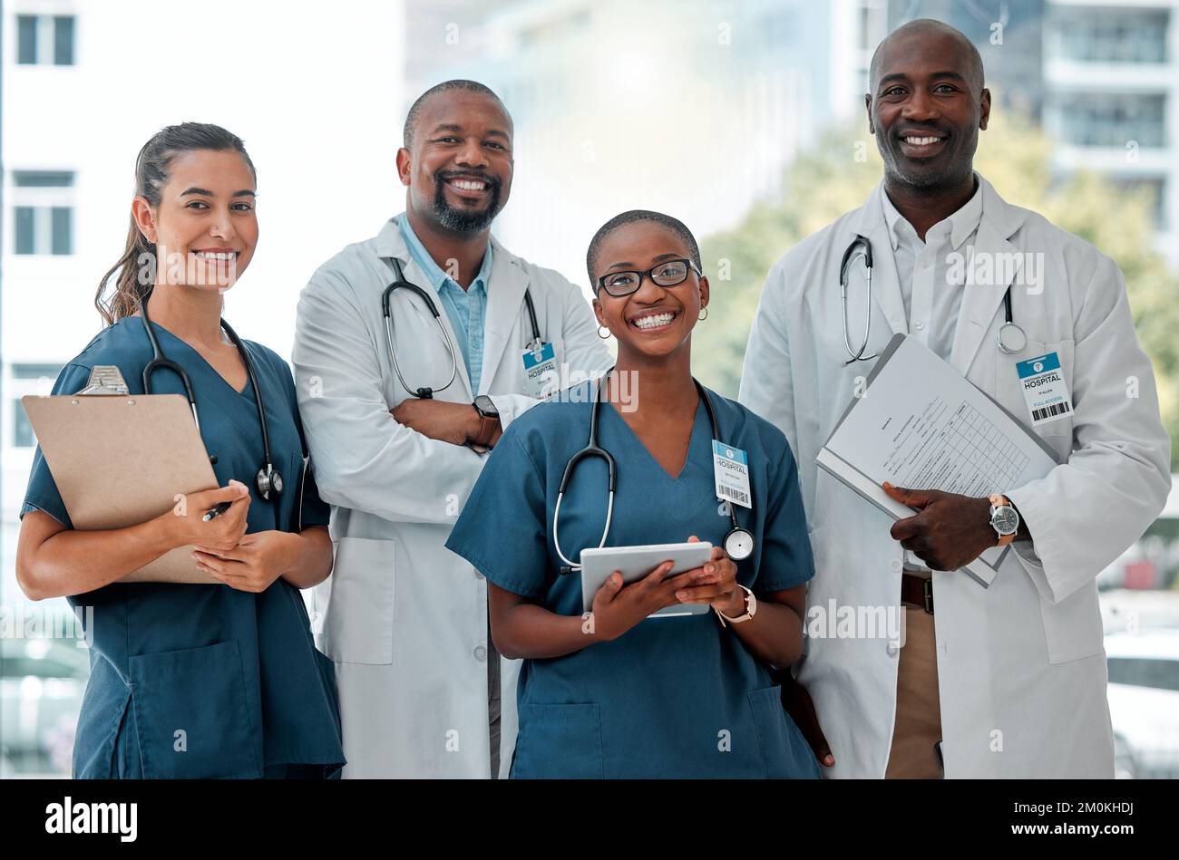 Gruppe von Ärzten und Krankenschwestern, die während der Arbeit in einem Krankenhaus mit gekreuzten Armen in einer Linie stehen. Content-Experte Mediziner, die lächeln Stockfoto