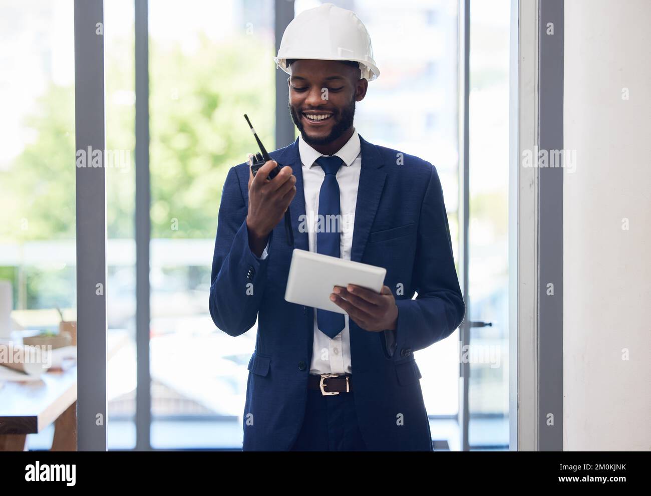 Black man, Tablet und Walkie-Talkie im Baumanagement, im Bürogebäudeplan oder in der Architekturplanung. Lächeln, glücklicher Ingenieur Stockfoto