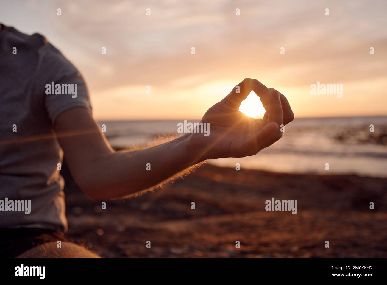 Strandmeditation, Sonnenuntergang und Hände des Menschen meditieren für Frieden, Freiheit und Chakra-Energie Heilung der Seele Aura. Sonnenschein, Lotus und spiritueller Yoga Stockfoto