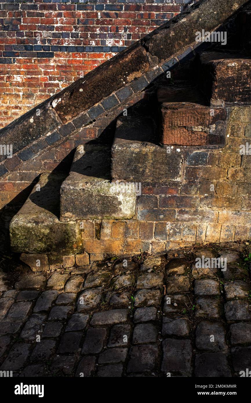 Abgenutzte Betontreppen neben der alten Wand Stockfoto