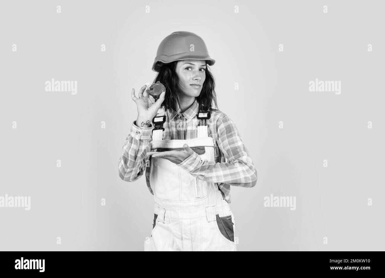 Anders denken. Architekt arbeitet mit Maßband. Weibliche Vorarbeiter auf der Baustelle. Schreiner Assistent tragen Schutzhelm. Mädchen in Stockfoto