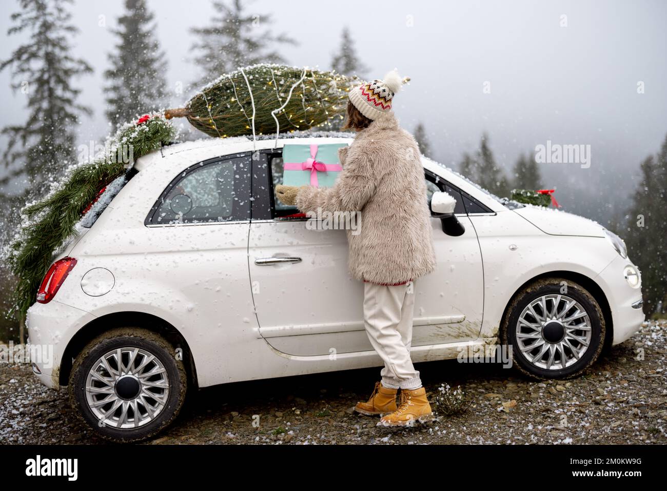 Frau fährt mit dem Auto mit Geschenken und Weihnachtsbaum auf der Bergstraße Stockfoto