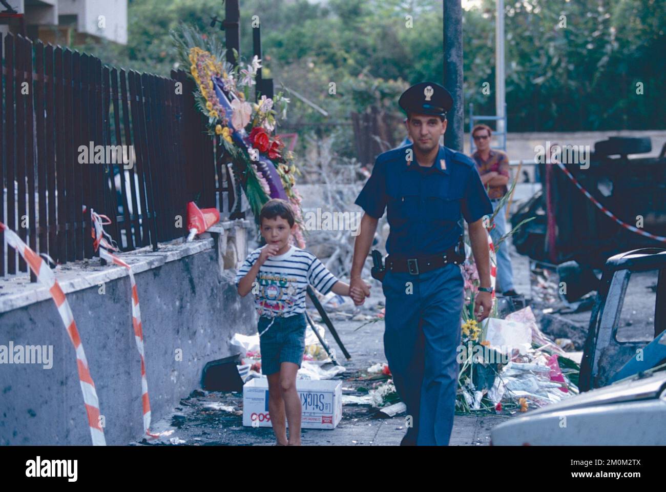 Ein Polizist begleitet ein Kind in der Via D'Amelio, Ort des Mafia-Terroranschlags, Palermo, Italien 1992 Stockfoto