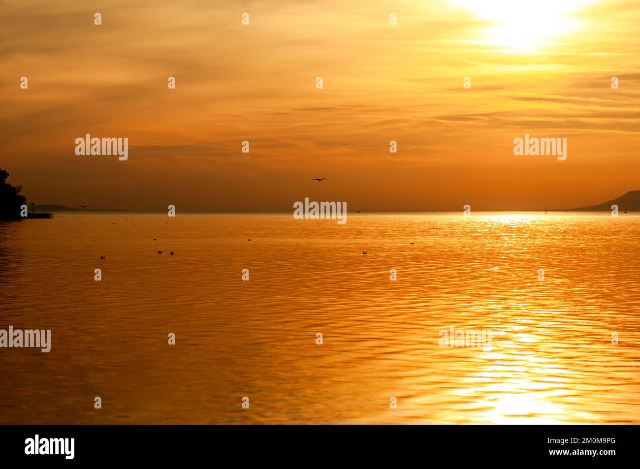 Die untergehende Sonne über dem Plattensee wurde in Balatonfoldvar, Balaton, Ungarn fotografiert. Balatonföldvár (Földwahr) ist ein beliebter Ferienort in Somogy Stockfoto