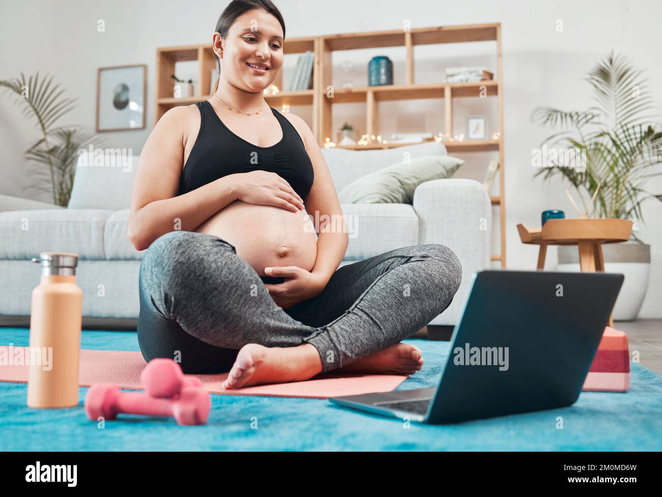 Laptop, Schwangerschafts-Yoga und Frau in einem Wohnzimmer, die zu Hause ein Fitnesstraining absolviert. Fitness, Meditation und schwangere Damen Streaming Pilates Stockfoto