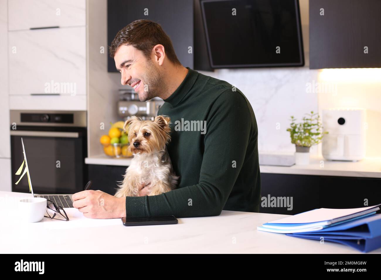 Attraktiver Mann, der von zu Hause aus mit seinem Schoßhund arbeitet Stockfoto