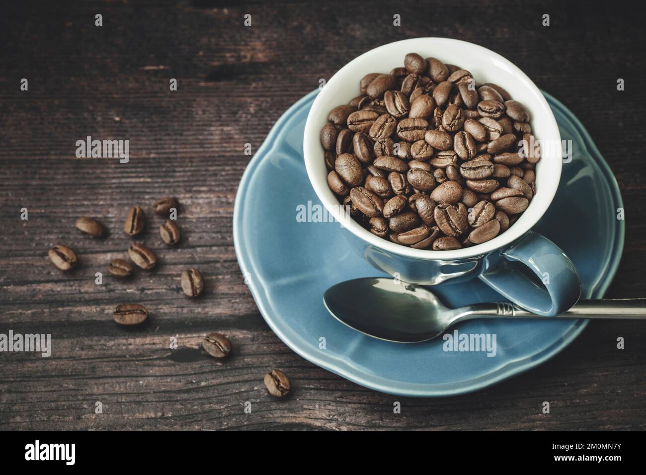 Geröstete Kaffeebohnen in blauer Tasse auf einem Holztisch Stockfoto