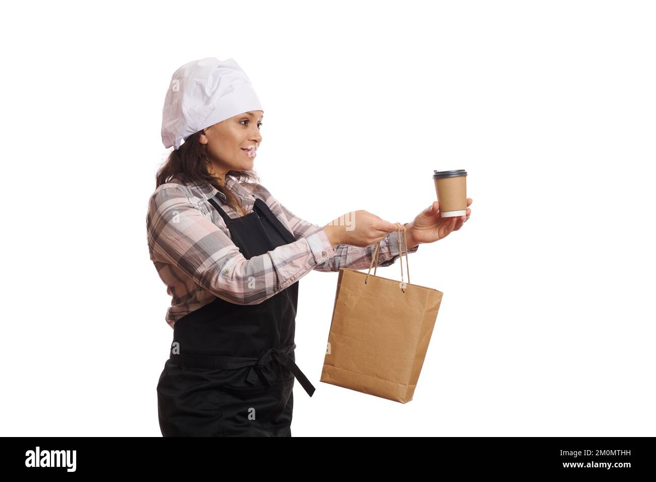 Seitenansicht: Freundliche Barkeeperin, Kellnerin hält eine Papiertüte und ein heißes Getränk zum Mitnehmen. Lieferung von Speisen und Getränken Stockfoto