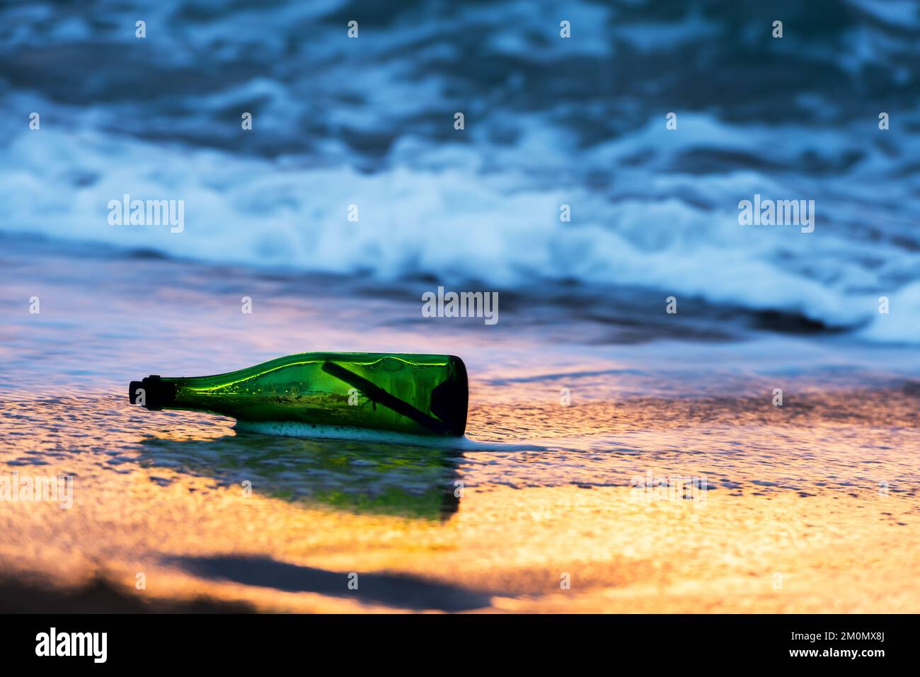 Grüne Glasflasche mit Papierbotschaft an der Küste des tropischen Strandes. Schiffbruch im Meer. Bitte um Hilfe. Save our Souls (SOS)-Konzept Stockfoto