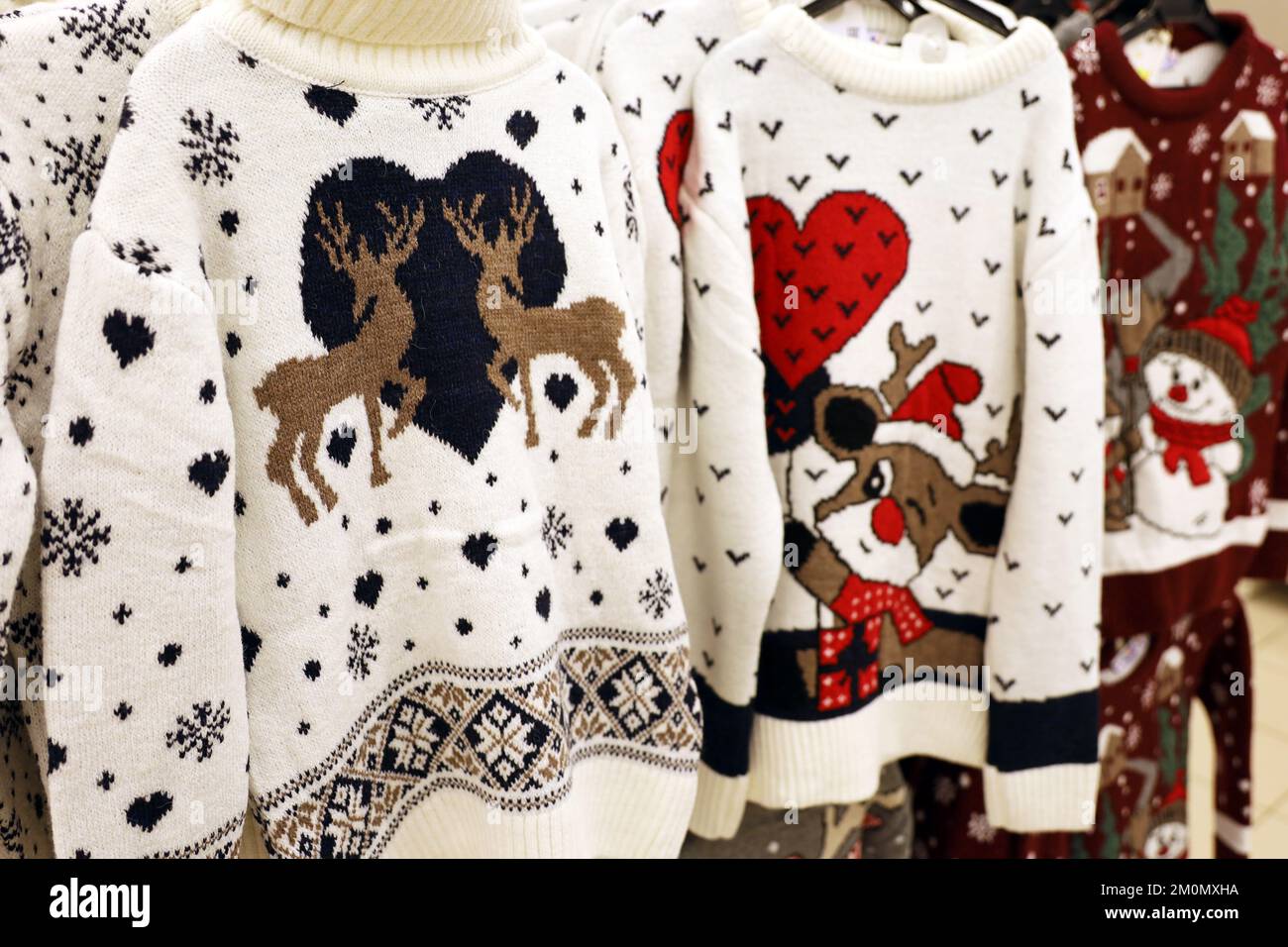 Strickpullover mit Weihnachtsmuster im Laden. Traditionelles, warmes Outfit für den Neujahrsurlaub Stockfoto